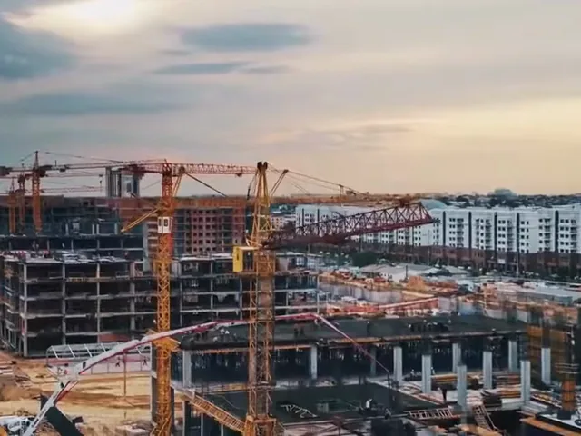 Construction site skyline with several tower cranes over a concrete structure.